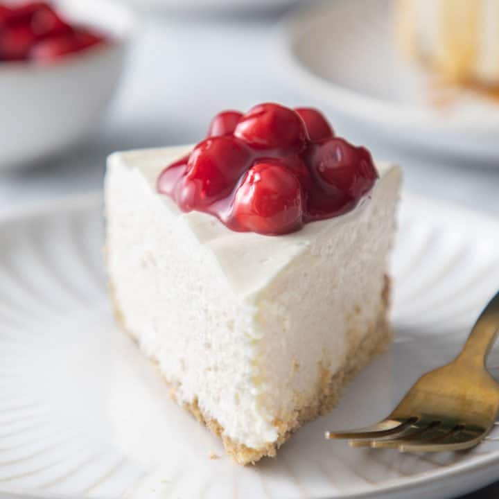 Close up front view of a slice of no-bake cheesecake on a white plate.