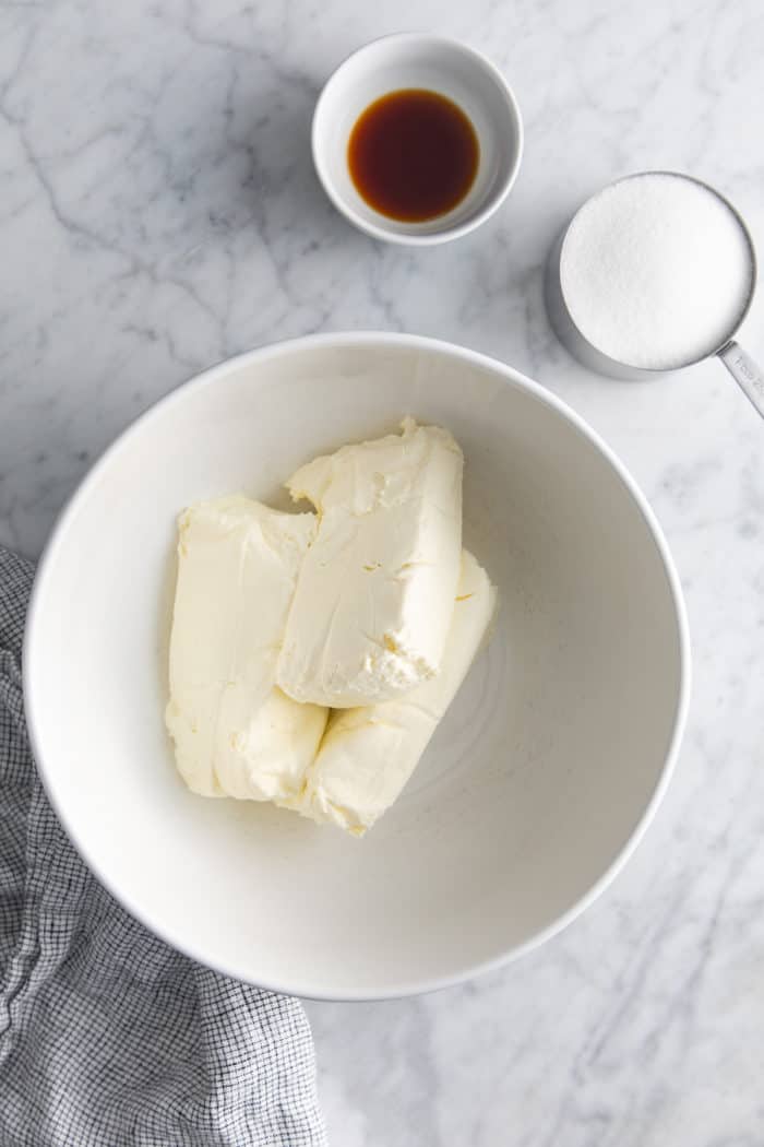 Ingredients for no-bake cheesecake filling arranged on a marble countertop.