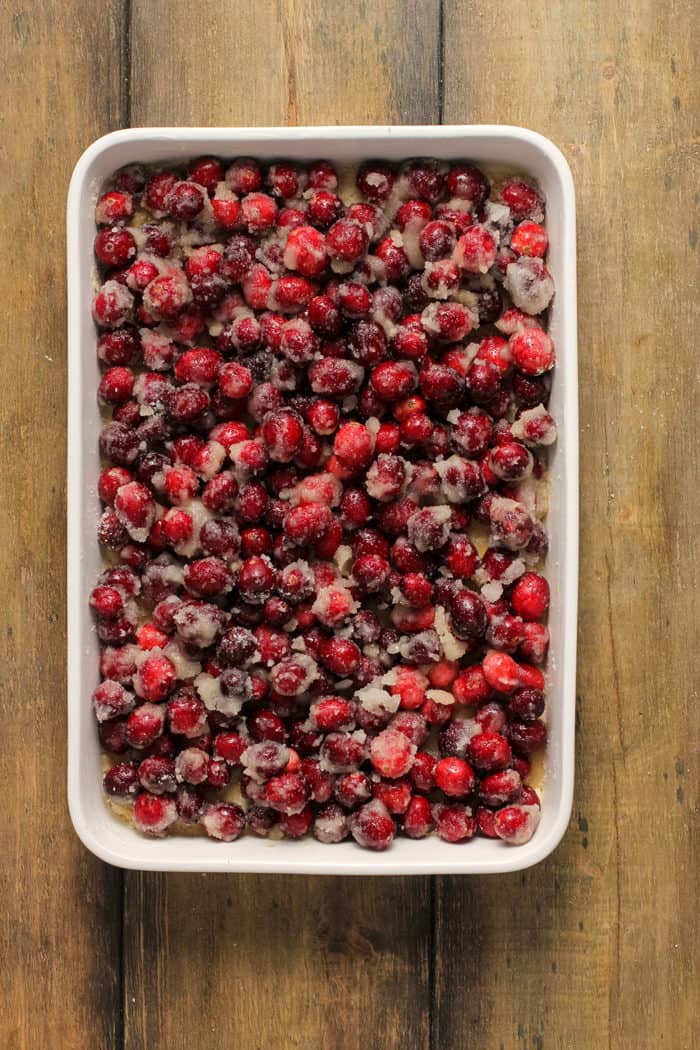 Cranberry filling on top of crumb bar crust in a white baking dish