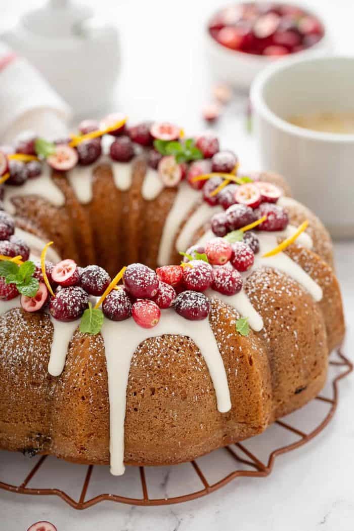 Baked cranberry orange bundt cake topped with glaze, fresh cranberries and orange zest