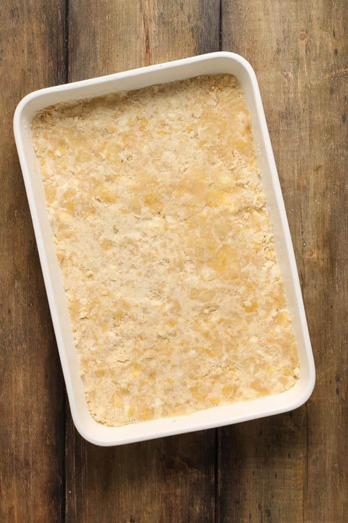 Crust for cranberry crumb bars pressed into the bottom of a white baking pan