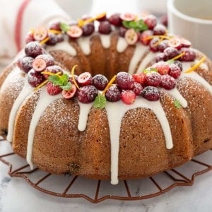 Cranberry bundt cake topped with glaze and fresh cranberries on a wire rack