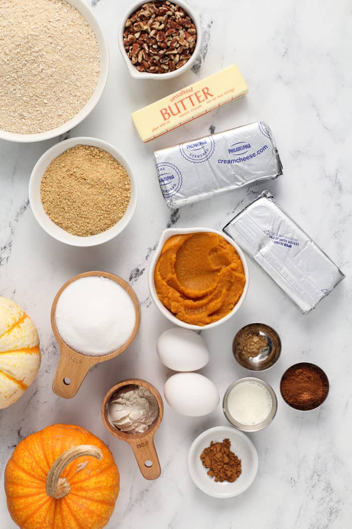 Pumpkin cheesecake bar ingredients arranged on a marble countertop