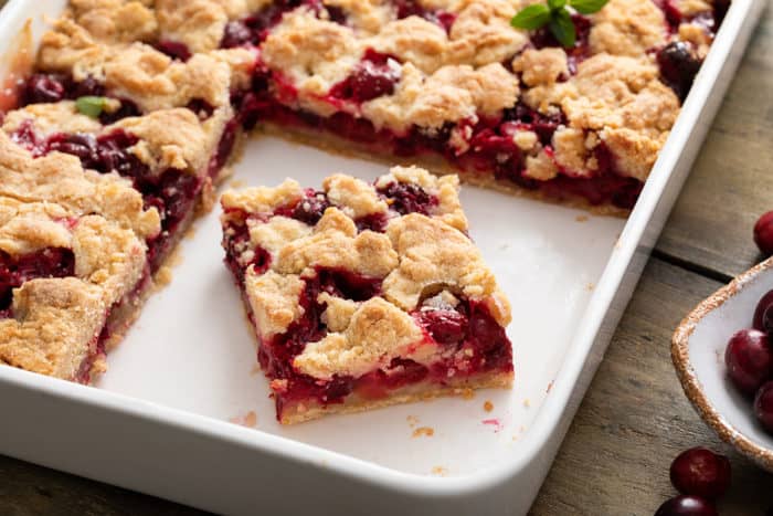 Close up of a sliced cranberry crumb bar in a white baking dish