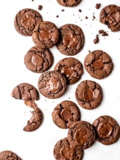 chocolate mint cookies scattered across a white surface, with some broken in half.