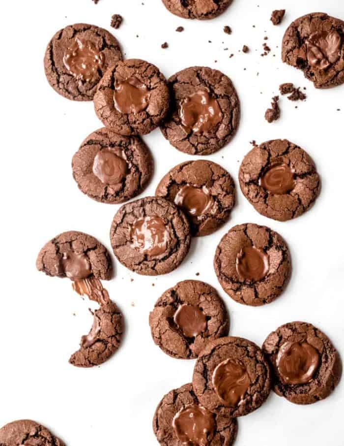 chocolate mint cookies scattered across a white surface, with some broken in half.