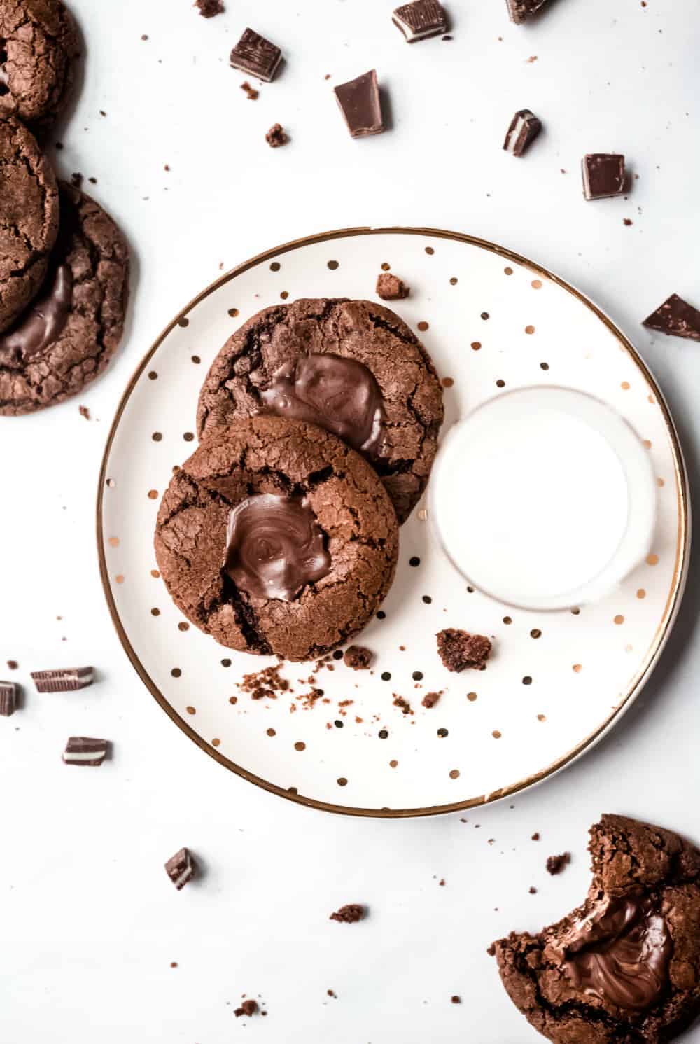 Two mint chocolate cookies on a white plate next to a glass of milk