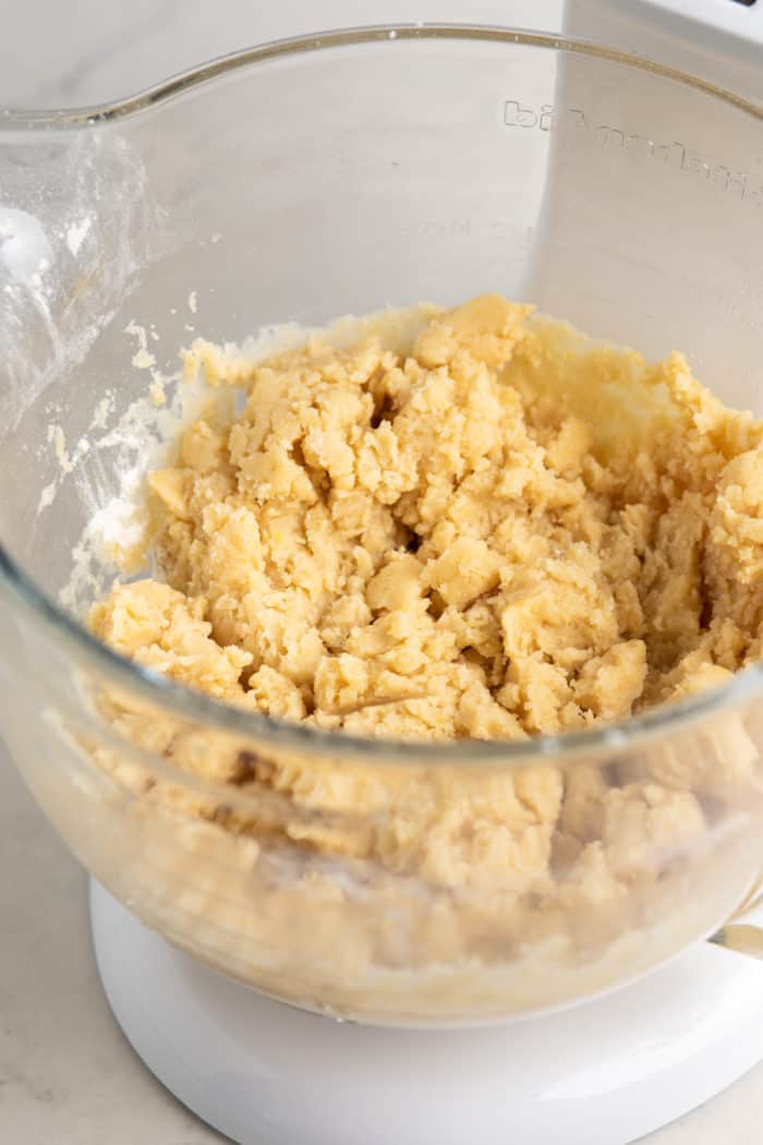 Dough for almond crescent cookies in the bowl of a stand mixer.