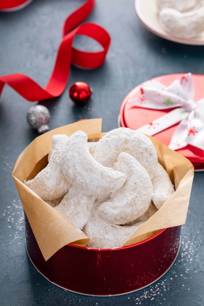 Almond crescent cookies arranged in a red tin.