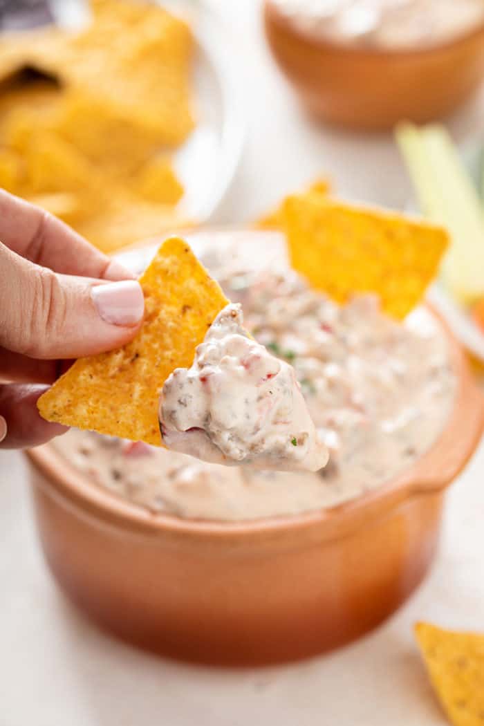 Scoop of spicy sausage dip on a tortilla chip