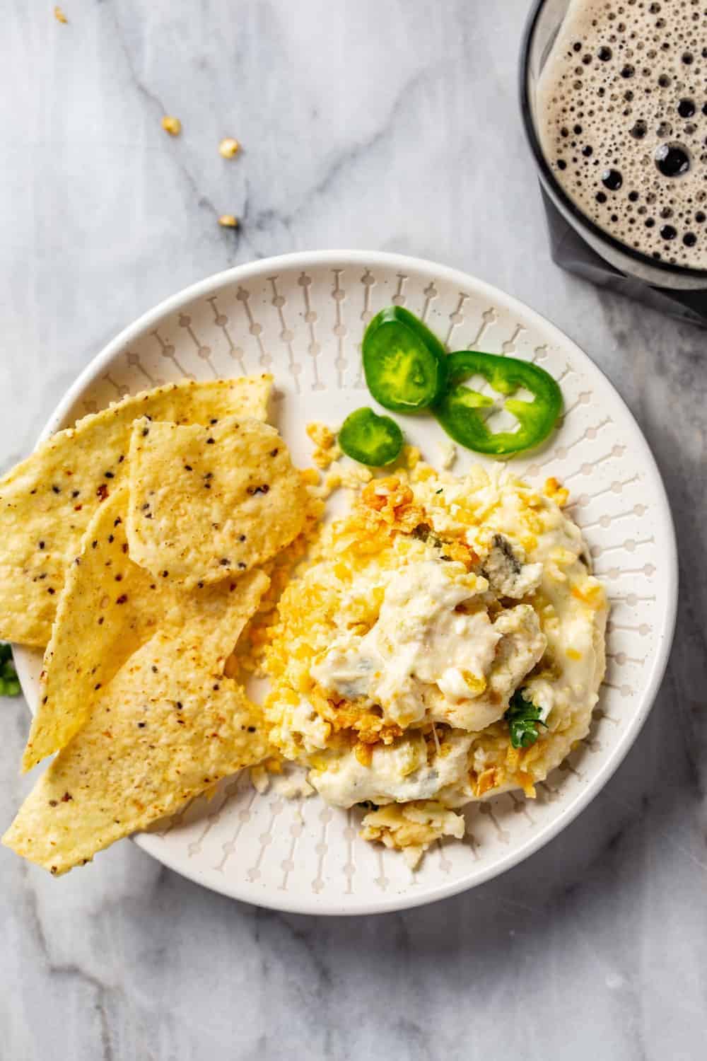 White plate with jalapeno popper dip and tortilla chips on it