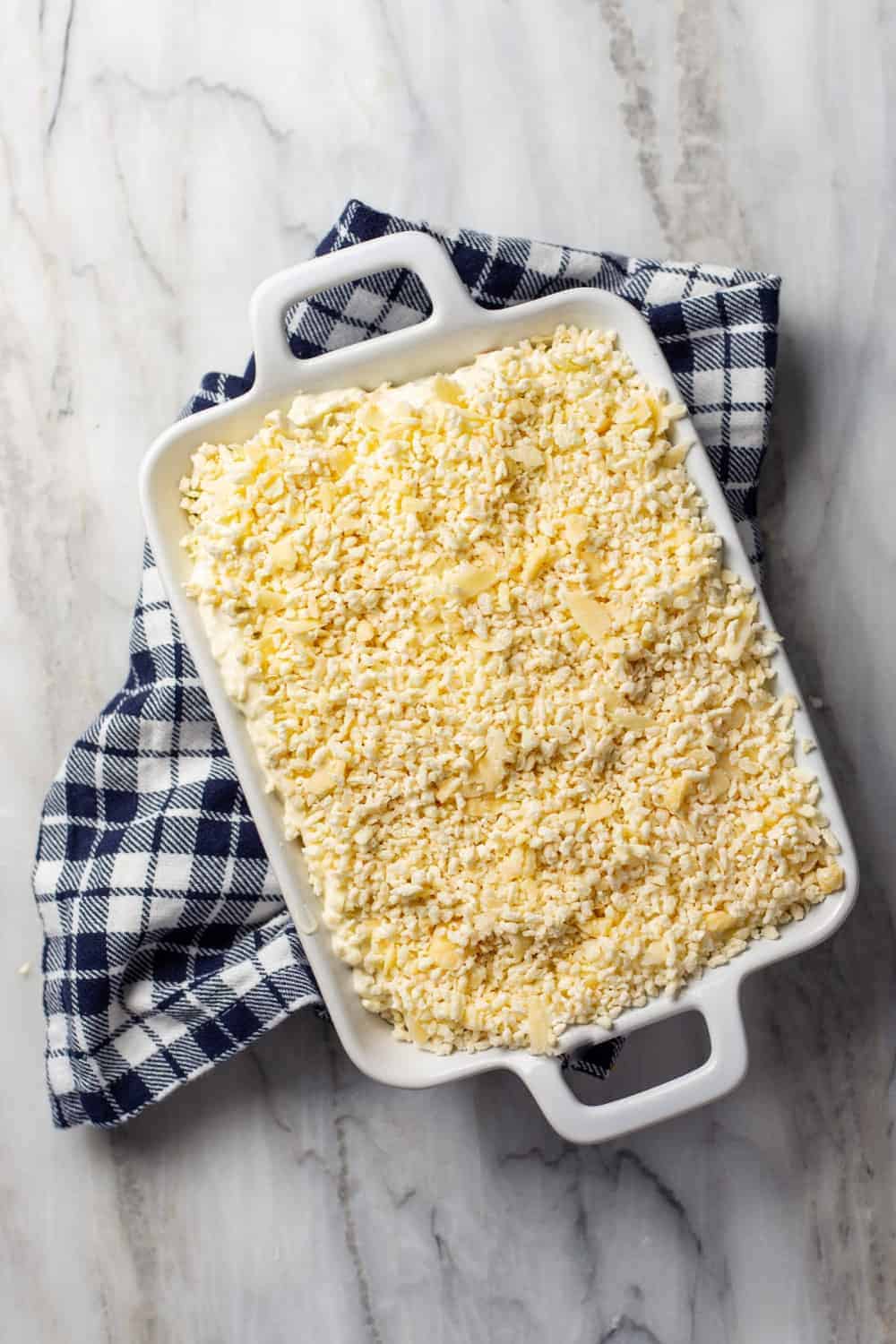 Jalapeno popper dip in a white baking dish, topped with panko and ready to bake