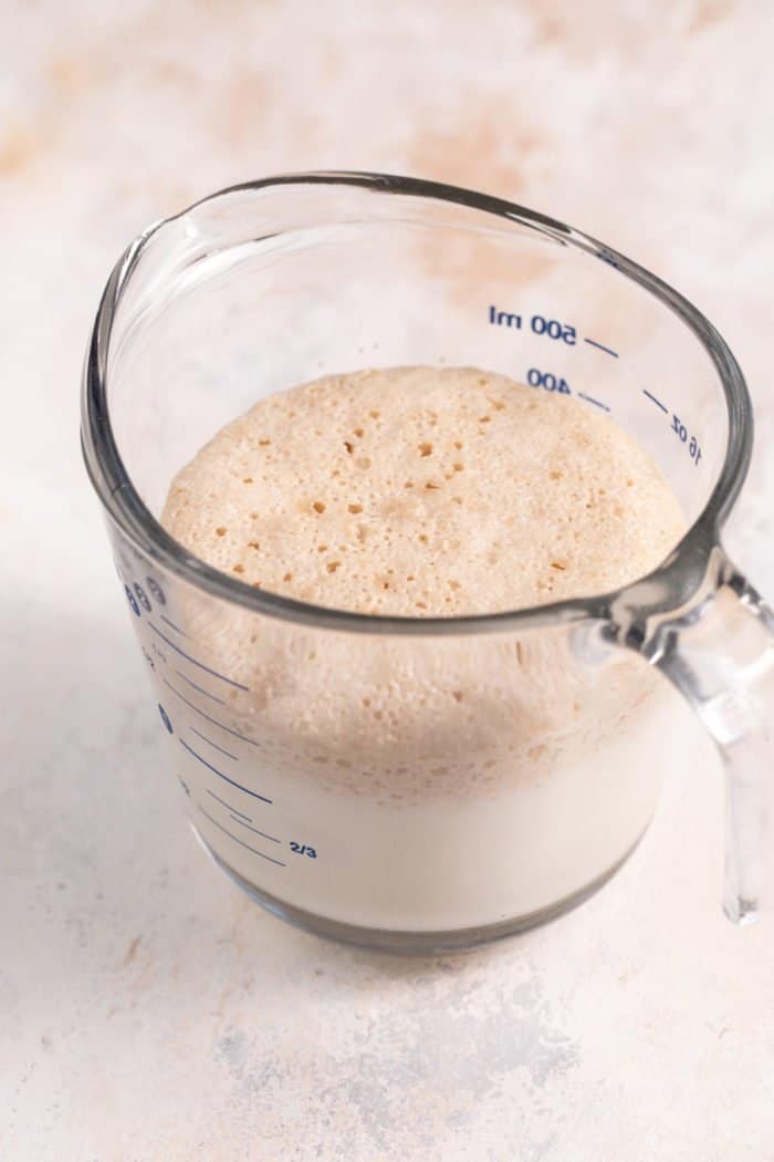Activated yeast in a glass measuring cup.