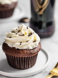 Guinness cupcake on a white plate with a bottle of Guinness in the background