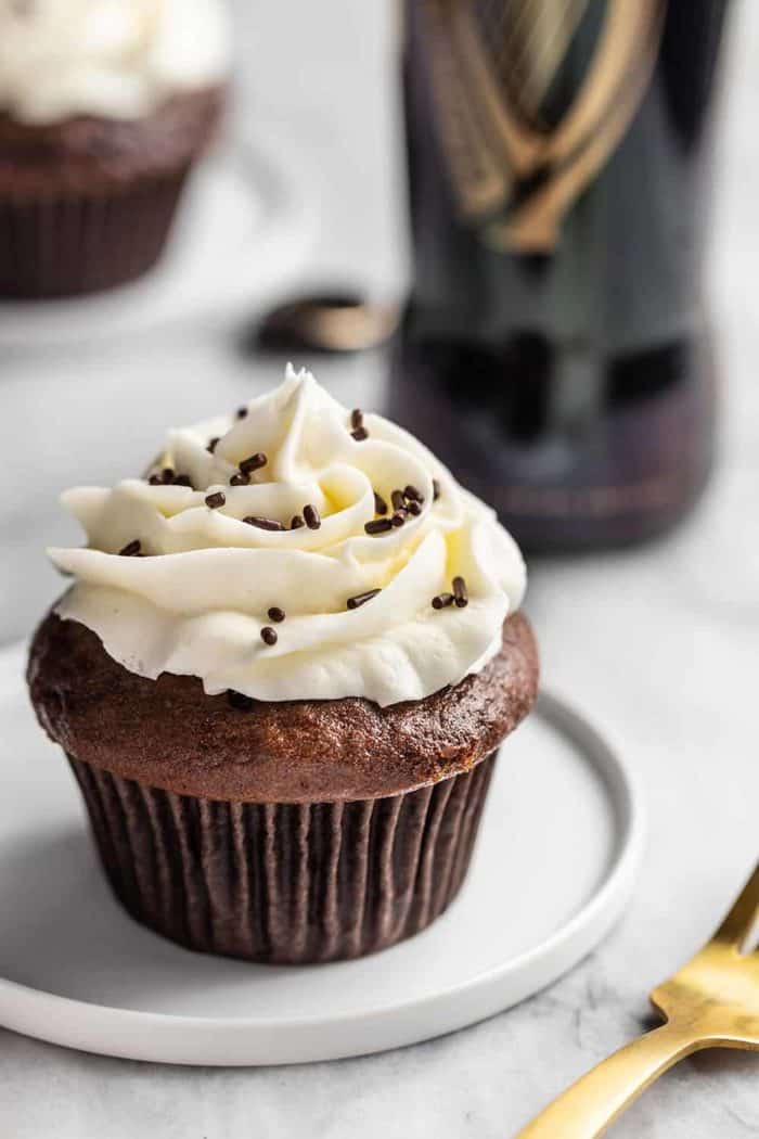 Guinness cupcake on a white plate with a bottle of Guinness in the background
