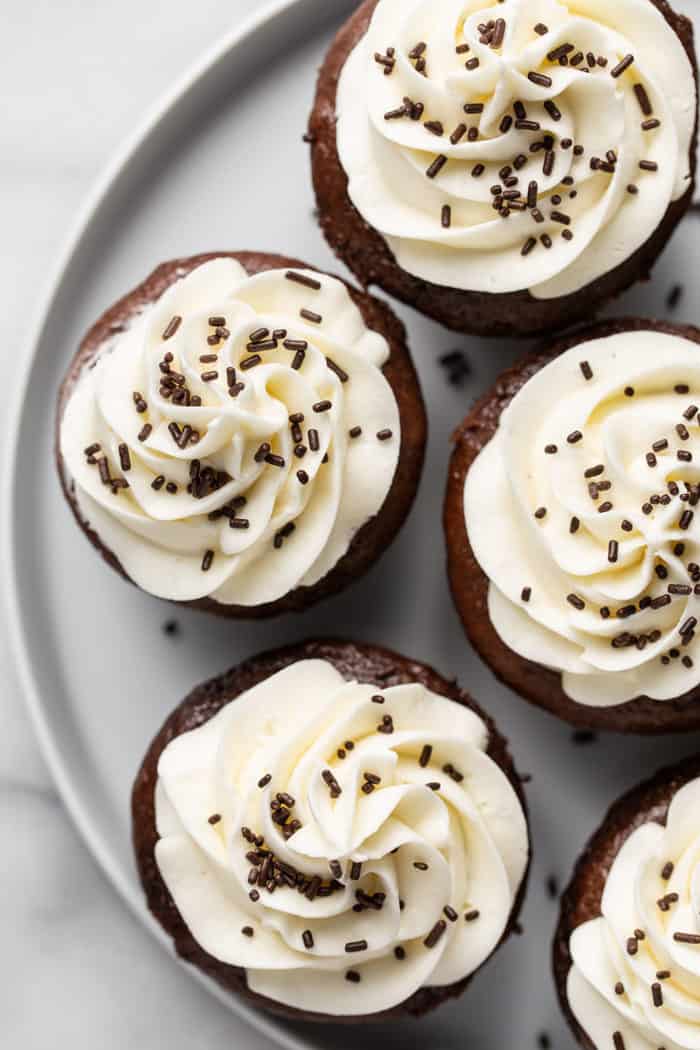 Overhead shot of several guiness cupcakes with vanilla buttercream frosting arranged on a white platter