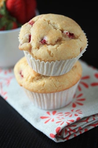 Two strawberry lemon muffins stacked on top of each other on a white and red decorated napkin