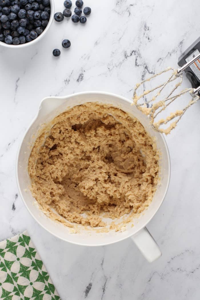 Butter, brown sugar, and white sugar beaten together in a white mixing bowl.