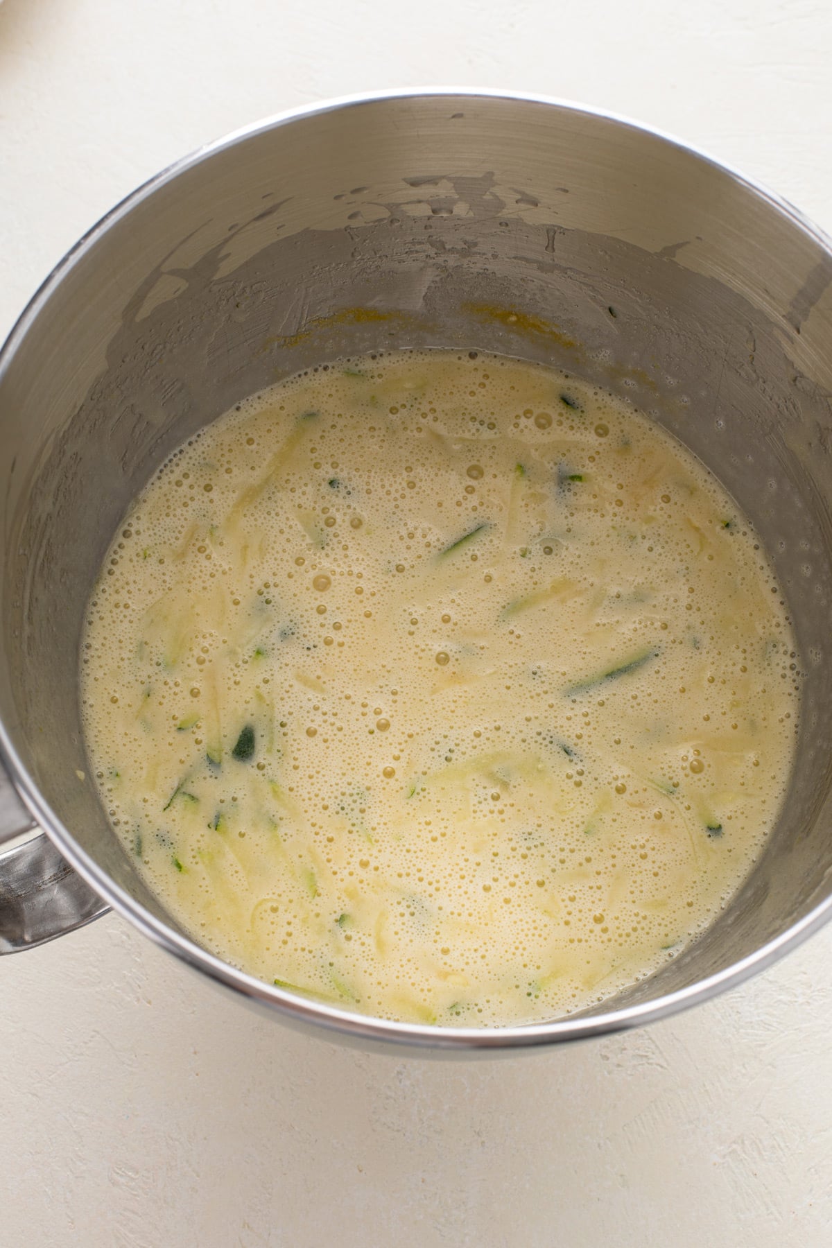 Wet ingredients for blueberry zucchini bread mixed in a metal mixing bowl.