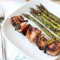 A Greek Kabob on a plate with a side of asparagus