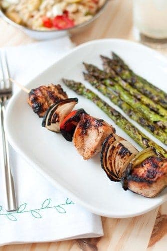A Greek Kabob on a plate with a side of asparagus