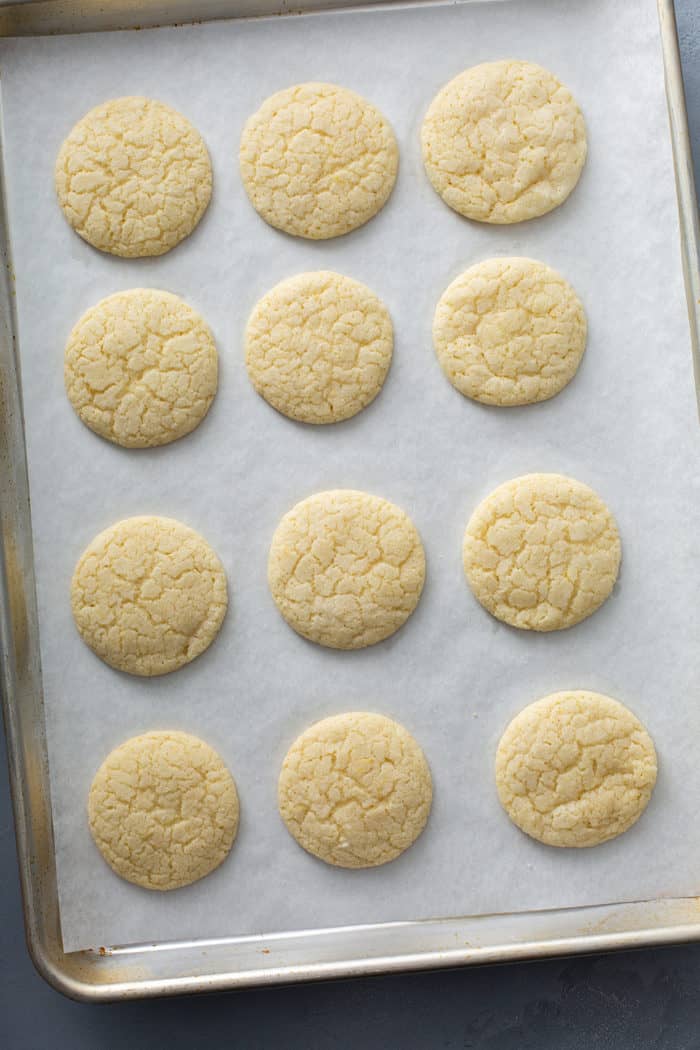 Baked chewy lemon sugar cookies on a parchment-lined baking sheet