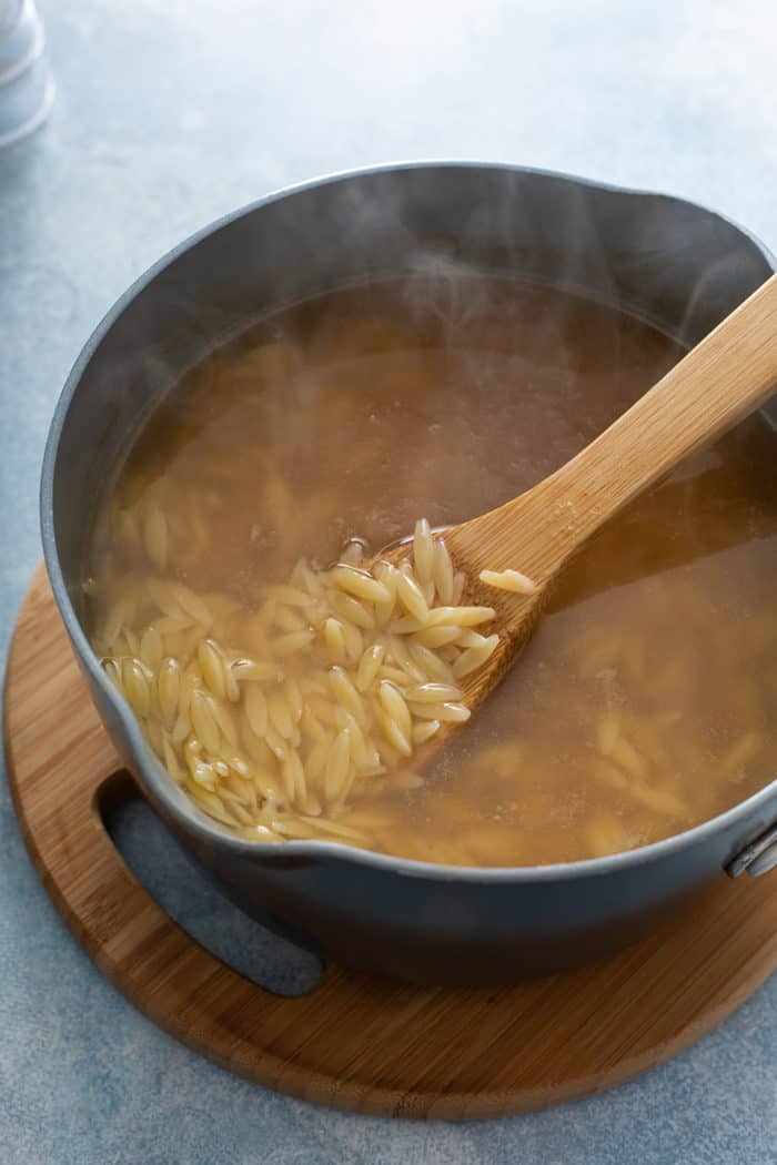 Orzo cooking in vegetable stock in a sauce pot
