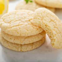 Chewy lemon sugar cookies in a stack. A cookie with a bite out of it is leaning against the stack.