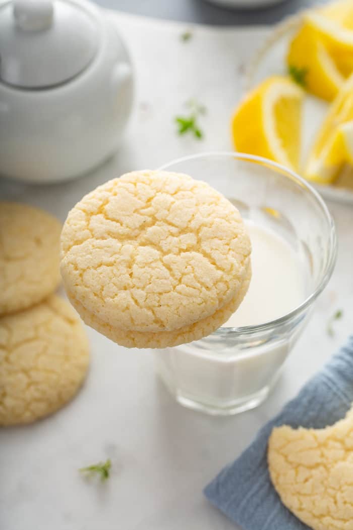 Chewy lemon sugar cookie balanced on the rim of a glass of milk