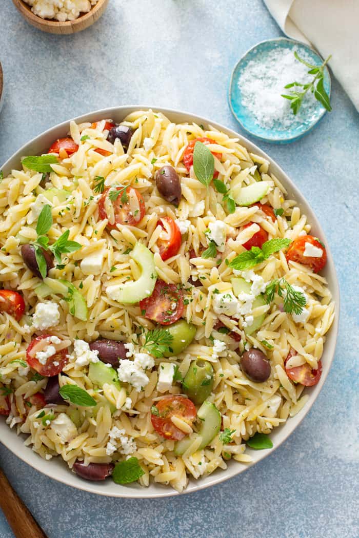 Overhead view of greek orzo salad in a serving bowl on a blue countertop