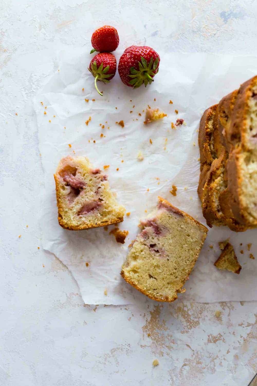 Remnants of a piece of strawberry bread on a white surface