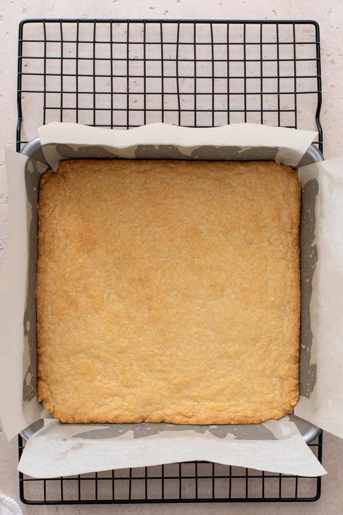 Baked shortbread base cooling on a wire rack.