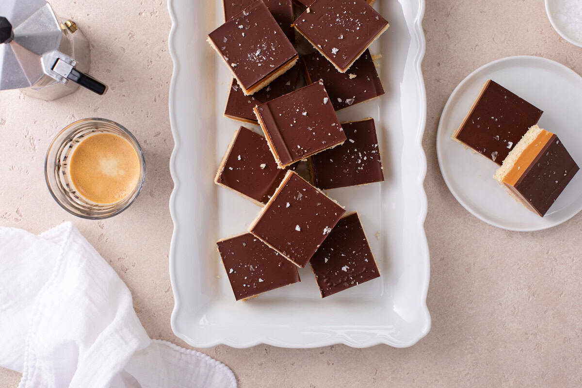 Overhead view of sliced millionaire shortbread arranged on a white platter.