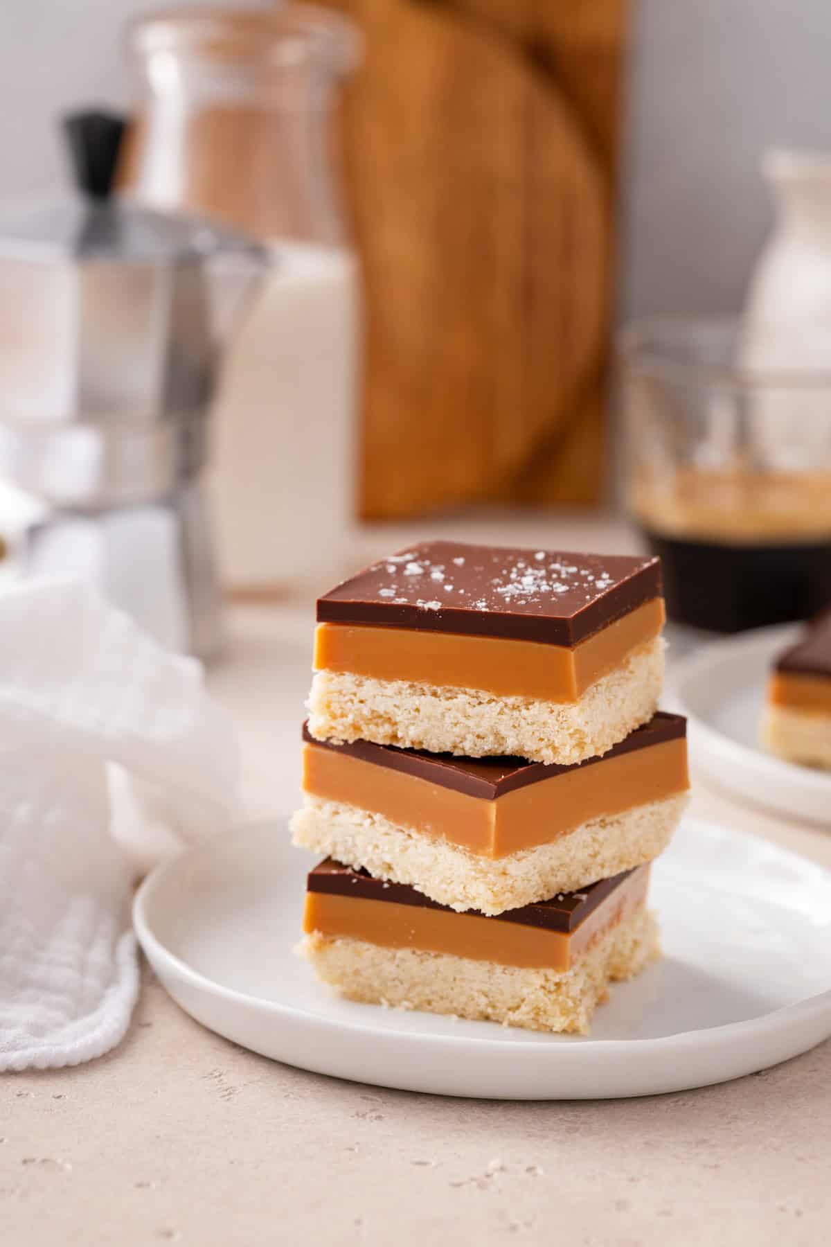 Three slices of millionaire shortbread stacked on a white plate.