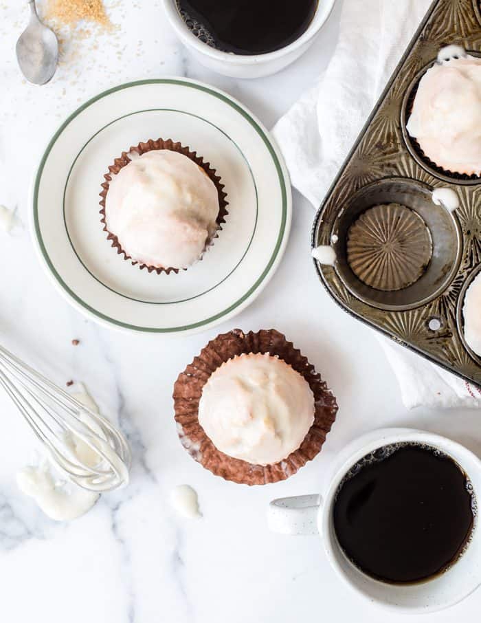 Overhead view of glazed donut muffins set on plates and in muffin tins on a white counter