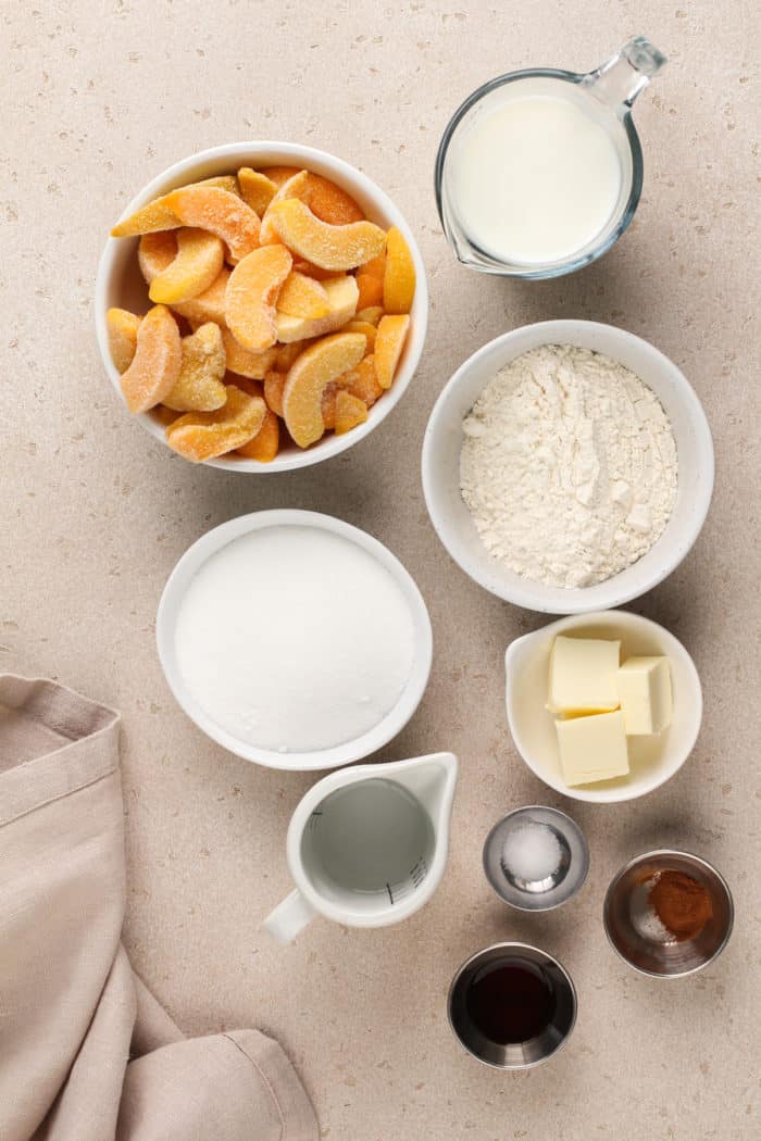 Homemade peach cobbler ingredients arranged on a beige countertop.