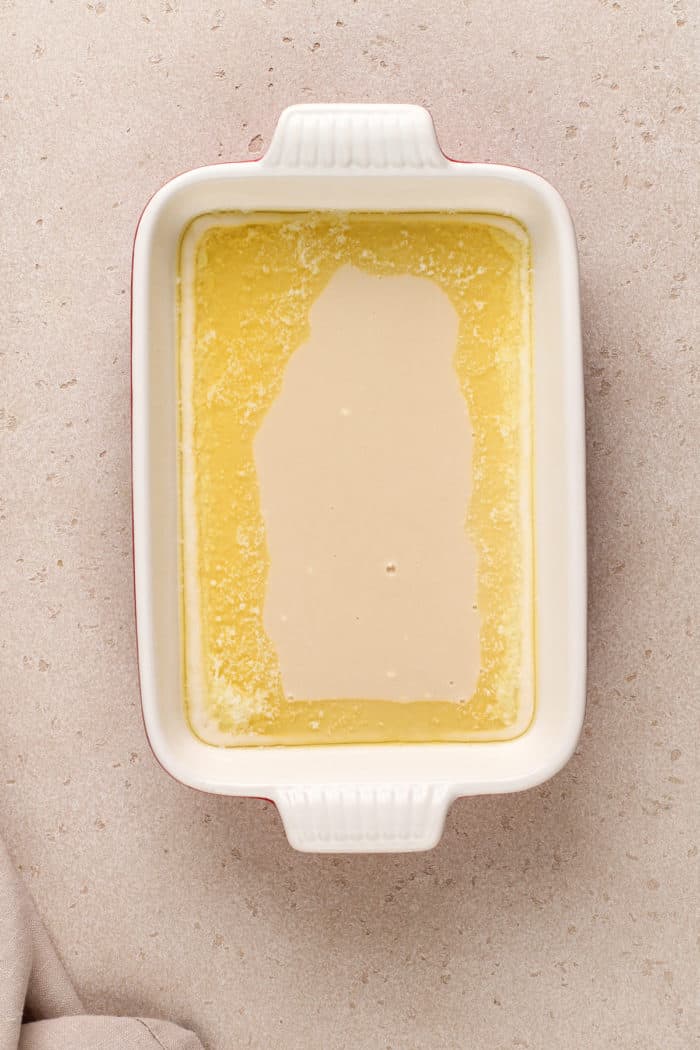 Melted butter in the bottom of a white baking dish.