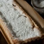 Custard apple tart sprinkled with powdered sugar on baking paper