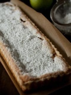 Custard apple tart sprinkled with powdered sugar on baking paper