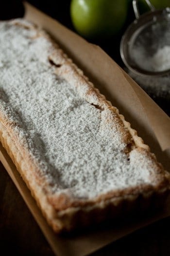 Custard apple tart sprinkled with powdered sugar on baking paper