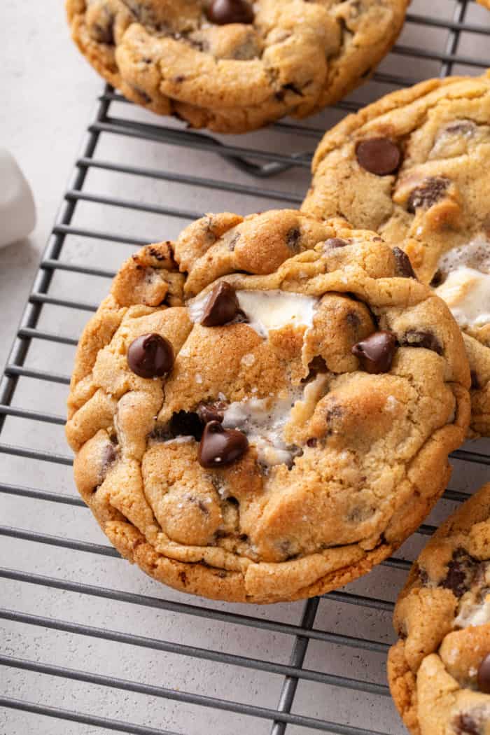 Close up of a giant s'mores cookie on a wire cooling rack, with marshmallow peeking through the top of the cookie.