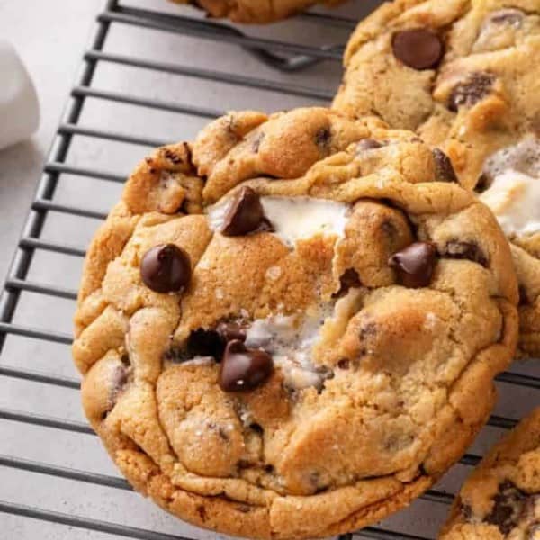 Close up of a giant s'mores cookie on a wire cooling rack, with marshmallow peeking through the top of the cookie.