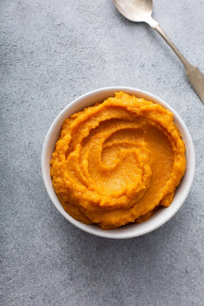 Butternut squash puree in a white bowl on a gray counter
