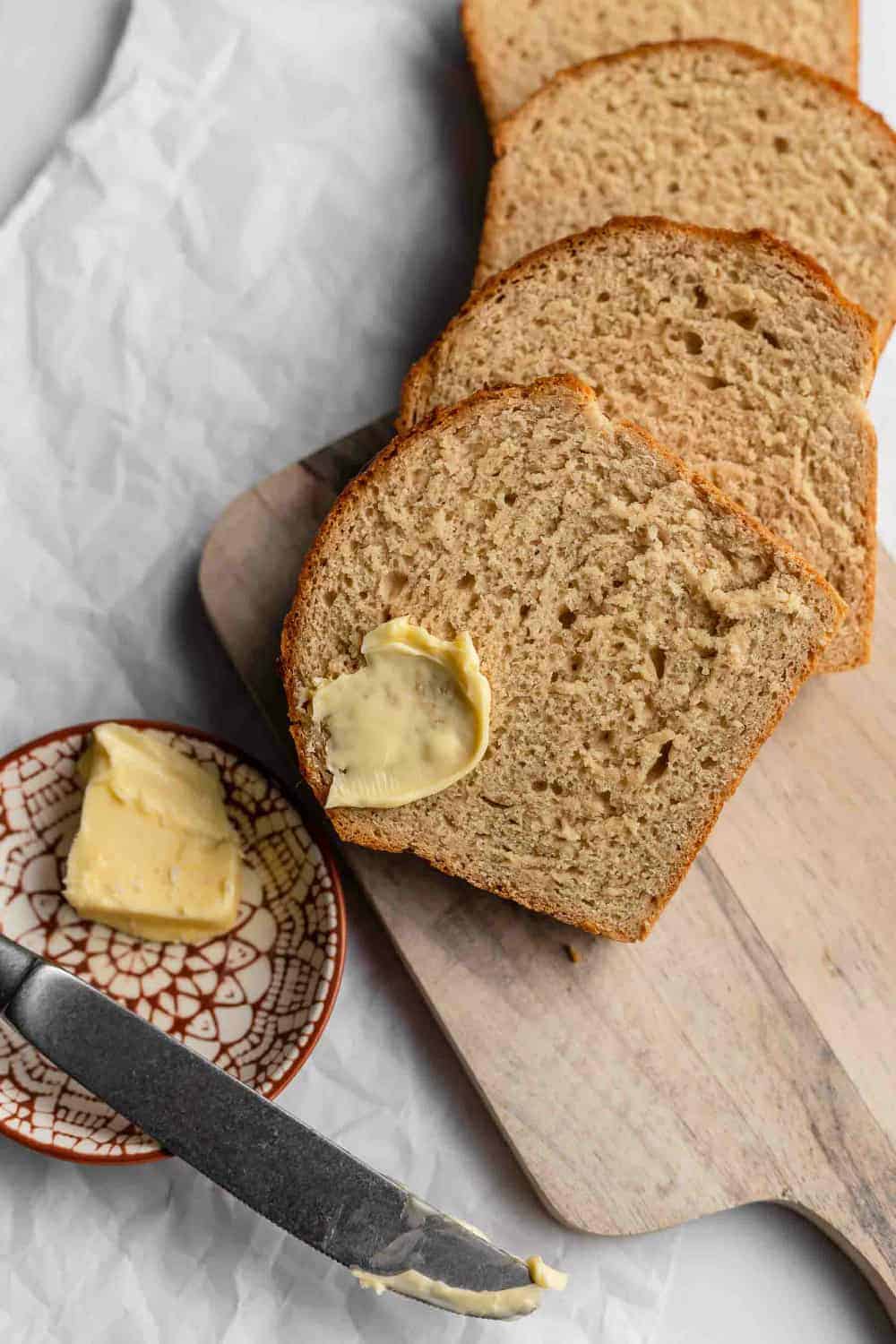 Buttered beer bread on a wooden board next to a plate of butter