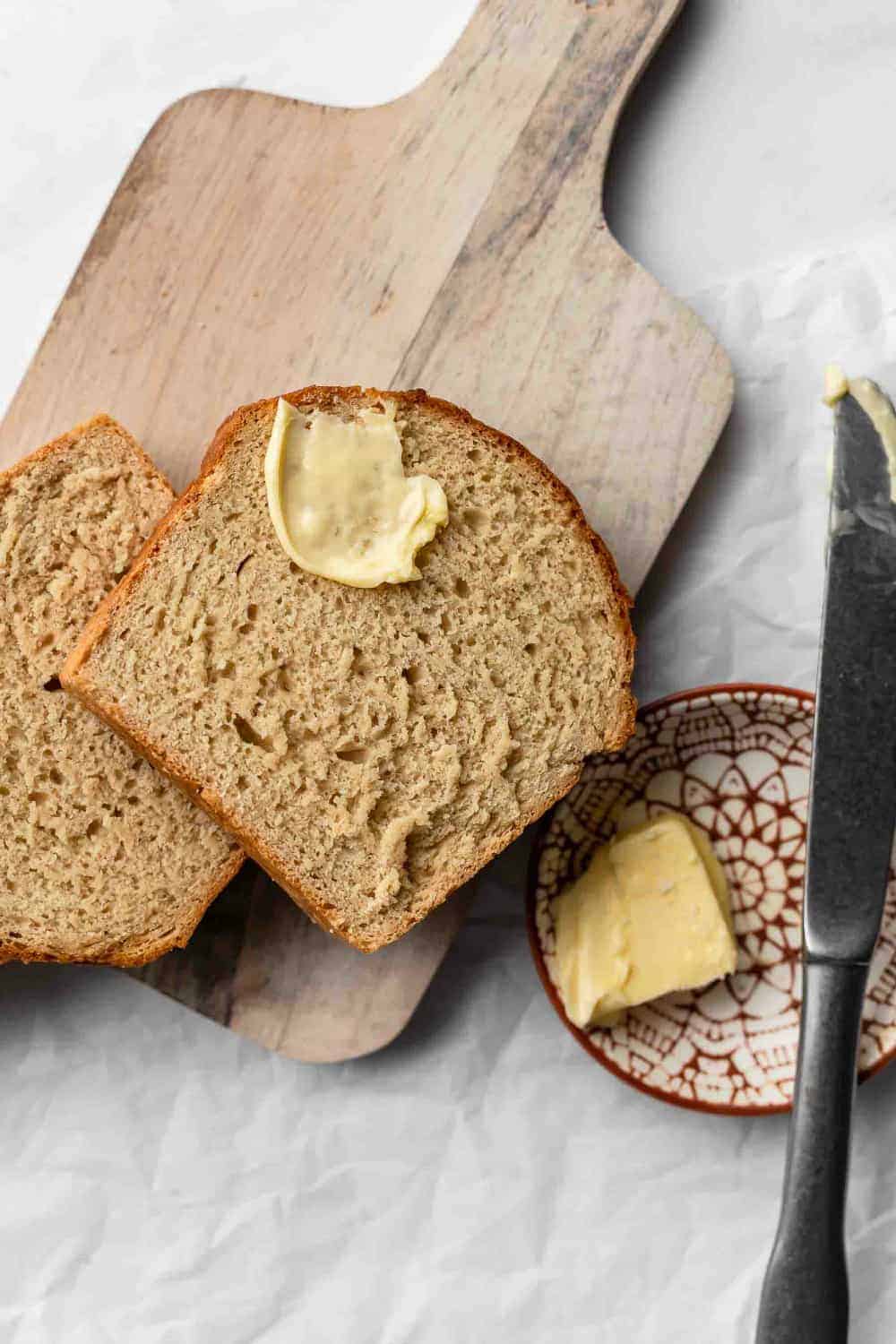 Slice of beer bread on a wooden board with a smear of butter on the bread