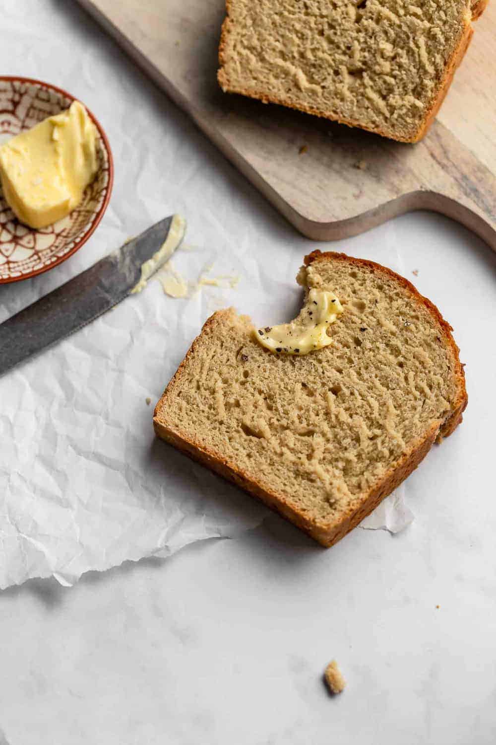 Slice of beer bread topped with butter, salt and pepper with a bite taken out of it