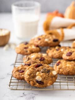 Pumpkin oatmeal cookies scattered on a wire cooling rack with a glass of milk in the background