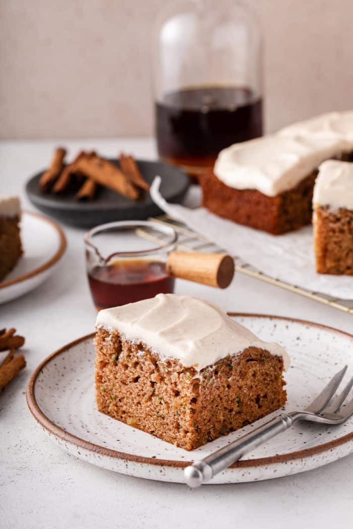 Plated slice of zucchini cake topped with maple cream cheese frosting.