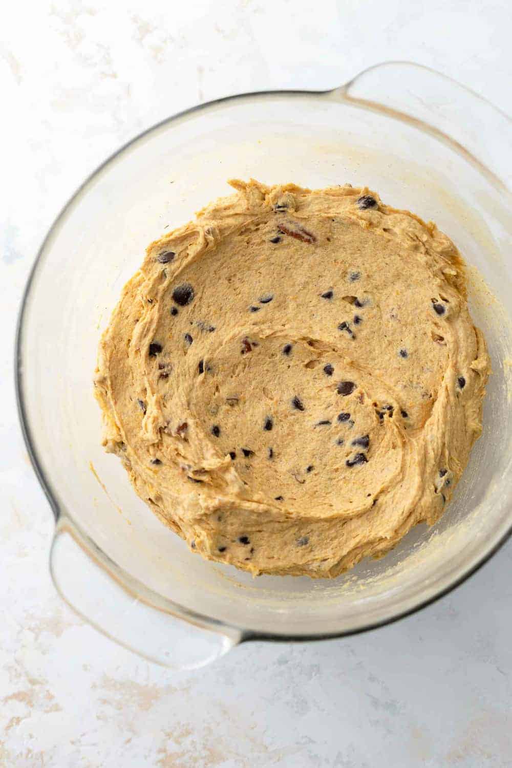 Pumpkin blondie batter with chocolate chips in a glass mixing bowl