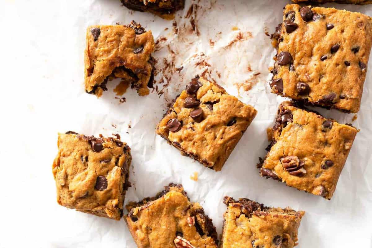 Warm, sliced pumpkin blondies with chocolate chips on parchment paper